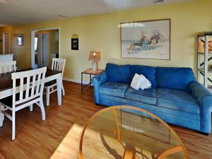 a living room with a blue couch and a table at Ocean Dunes 306 in Kure Beach