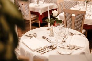 un tavolo con una tovaglia bianca e un fiore bianco sopra di Apartment Hotel Elvis a Ortisei