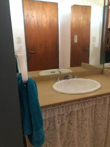 eine Badezimmerablage mit Waschbecken und Spiegel in der Unterkunft Hogar de luz in Olavarría