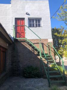 eine Treppe, die zu einer roten Tür in einem Gebäude führt in der Unterkunft Hogar de luz in Olavarría