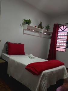 Un dormitorio con una cama con almohadas rojas y una ventana. en Zen Maharani Guesthouse - Qt nº 2, en Bauru