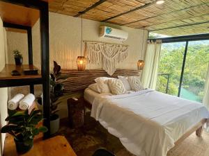 a bedroom with a bed and a large window at Costeño River Minca in Minca
