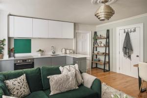 a living room with a green couch and a kitchen at Chic Georgian Escape near Royal Crescent in Bath