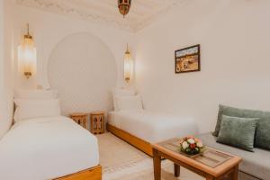 a room with two beds and a couch and a table at Riad Al Mechouar in Marrakech