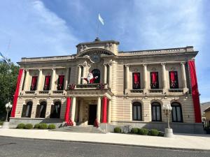 a large white building with red shutters on it at Departamento a media cuadra de plaza central in Tandil