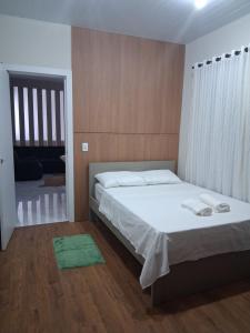 a bedroom with a bed with white sheets and a green rug at Apartamento moderno próximo ao centro in União da Vitória