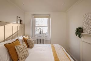 a bedroom with a white bed with pillows and a window at Chic Georgian Escape near Royal Crescent in Bath