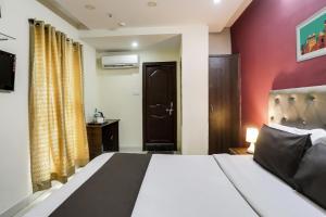 a bedroom with a bed and a red wall at Collection O Lotus Grand in Hyderabad