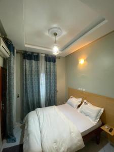Un dormitorio con una cama blanca con una ventana. en Hôtel 2K, en Yaoundé 7 fotos más
