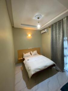 Un dormitorio con una cama blanca con una ventana. en Hôtel 2K, en Yaoundé