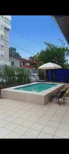 a swimming pool with two chairs and an umbrella at American Hostel e Pousada in Joinville