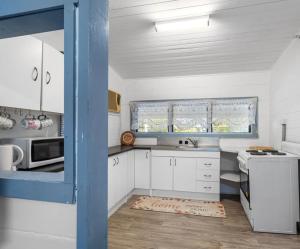 a kitchen with white cabinets and a blue door at Syntax Cottage in Coalfalls