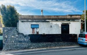 een wit huis met een raam en een stenen muur bij Gli occhi del vulcano in Linera