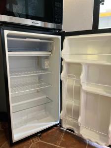 una nevera vacía con la puerta abierta y un microondas en Casa Olas, en Quepos