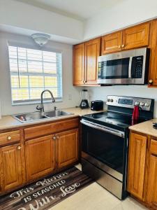 a kitchen with a stove and a sink and a microwave at Discovery Cove Sarasota in Sarasota
