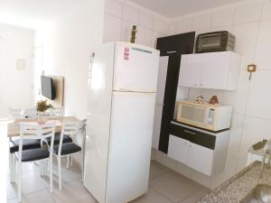 a kitchen with a refrigerator and a table with a microwave at Apartamento superior Boracéia in Bertioga