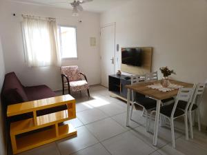 a living room with a table and a couch and a television at Apartamento superior Boracéia in Bertioga