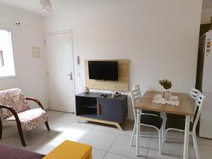 a living room with a table and a tv at Apartamento superior Boracéia in Bertioga