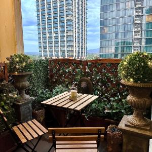 een tafel en banken op een balkon met gebouwen bij UNIQUE CBD BOTIQUE STAY, BALCONY,NETFLIX,FREE WIFI,FREE Tram,FREE Bus,Walk to Rundle St, UniAdelaide, RAH, Casino, Pubs, Cafes in Adelaide