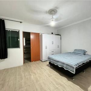 a bedroom with a bed and a closet in it at Quartos em Arraial do Cabo in Arraial do Cabo