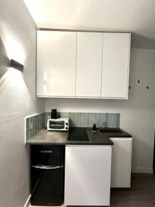 een keuken met witte kasten en een broodrooster bij Charming Studio - Trail in La Celle-sous-Gouzon