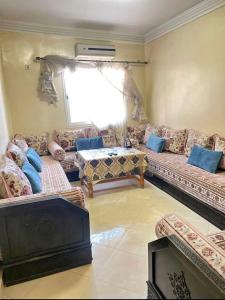 ein Wohnzimmer mit Sofas und einem Kamin in der Unterkunft Appartement Calme près du Stade Tamensourt in Oulad Akkou
