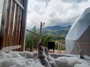 a person laying in a hot tub with their feet in the snow at Glamping Guacharaca Silvanía Cundinamarca in Silvania