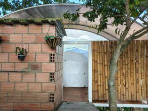 an open door to a brick building with a tree at Glamping Guacharaca Silvanía Cundinamarca in Silvania +1 photo
