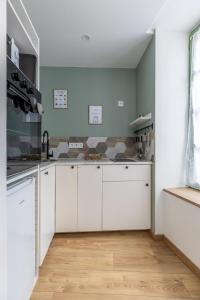Eine Küche mit weißen Schränken und Holzboden in der Unterkunft LE CATELE - Studio RIOM - 3 pers - Vulcania - Puy de Dôme - Proche Clermont Ferrand in Riom