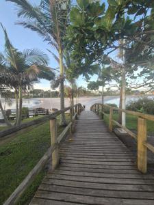 イタポアにあるHotel Recanto das Pedrasのヤシの木が生えるビーチへ続く木造遊歩道