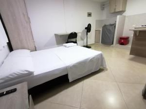 a bedroom with a white bed and a black chair at Tu Loft Ideal Amoblado, Wifi, Parqueadero y Confort in Bucaramanga