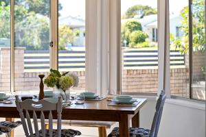 ein Esszimmer mit Tisch und Stühlen und Fenstern in der Unterkunft Sunny Days Villa Vincentia in Vincentia + 28 Fotos