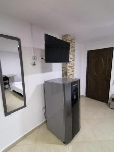 a room with a small refrigerator and a television on a wall at Tu Loft Ideal Amoblado, Wifi, Parqueadero y Confort in Bucaramanga