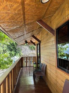 un portico di una casa di legno con una sedia e una finestra di Oceana a Padre Burgos Altre 36 foto