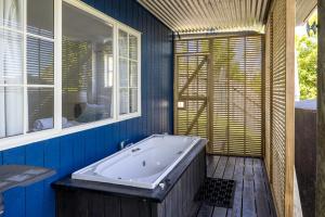 ein blaues Bad mit einer Badewanne und einem Fenster in der Unterkunft The Garden Room by Waiheke Pure in Waiheke Island + 18 Fotos