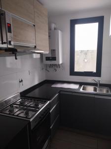 a kitchen with a stove and a sink and a window at Las Pircas PB in Alta Gracia