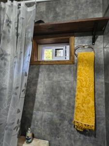 a bathroom with a yellow shower curtain and a window at Refugio CASA NAVE Torre del Bosque in San Eduardo del Mar
