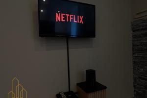 een televisie met een netflix-bord op een muur bij Le Cocon Rollin - Moderne & Confort in Roanne +5 foto's