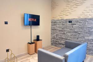 een woonkamer met een tv tegen een stenen muur bij Le Cocon Rollin - Moderne & Confort in Roanne