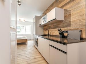 Hopfgarten Alpin Living Top 2 في هوبفغراتن إم بريكسنتال: مطبخ بدولاب بيضاء وجدار خشبي