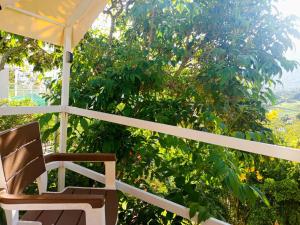 Cabaña tipi ñeque con vista al bosque في سيلفانيا: كرسي يجلس على الشرفة مع مظلة