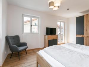 a bedroom with a bed and a chair and a television at Hopfgarten Alpin Living Top 3 in Hopfgarten im Brixental