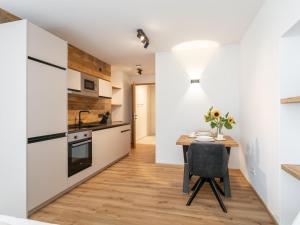 Hopfgarten Alpin Living Top 4 في هوبفغراتن إم بريكسنتال: مطبخ فيه دواليب بيضاء وطاولة عليها ورد +24 صورة