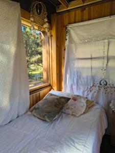 a white bed with a window in a bedroom at Refugio CASA NAVE Torre del Bosque in San Eduardo del Mar