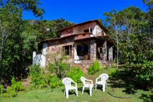 um grupo de cadeiras brancas em frente a uma casa em Espaço Gaia em Palmeiras