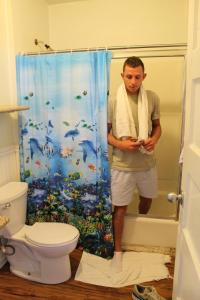 ロサンゼルスにあるベニス ビーチ ホステルのタオルを持ってシャワーを浴びている男