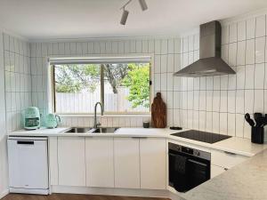 a white kitchen with a sink and a window at Senja in Torquay