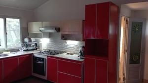 a kitchen with red cabinets and a stove at Ecotropicfarmhouse in Cerro Azul