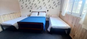 una camera con 2 letti con lenzuola blu e cuscini bianchi di La Nona a General Belgrano