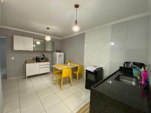 a kitchen with a table and yellow chairs in it at Apartamento á 5 minutos do centro in Garanhuns